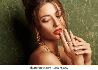 Portrait of a stunning young woman with evening make-up and hairstyle wearing golden jewelry in a luxury apartment. Classic vintage interior. 