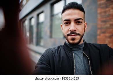 Portrait Of Stylish Arab Beard Man Wear Grey Turtleneck And Black Jaket. Arabian Model Guy Make Selfie By Camera.