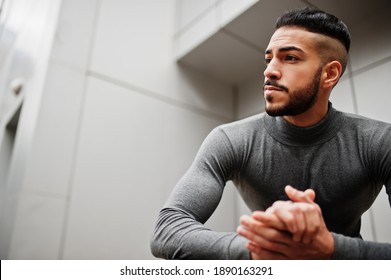 Portrait Of Stylish Arab Beard Man Wear Grey Turtleneck. Arabian Model Guy Against Steel Wall Squat.