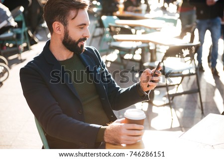 Happy bearded businessman speaking on smartphone in city
