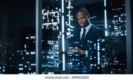 Portrait of Stylish Black Businessman Using Laptop, Looking out of Window on a City. successful African-American CEO Working on Computer, Working Hard Late At Night to Achieve Best Results - Shutterstock ID 2090541820