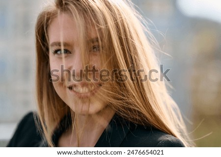 Young pretty woman in a pink blazer stands in front of an orange wall