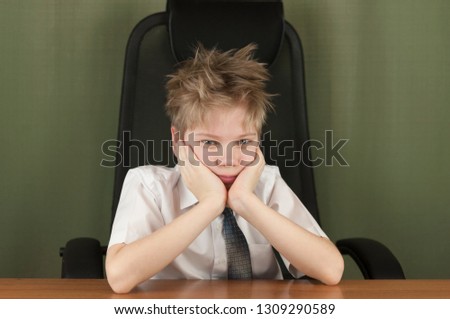 Portrait of stylish business child sitting at workplace. Cute caucasian boy imitating businessperson or office worke