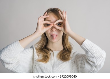 Portrait of a stylish and cheerful girl on a white background in the studio who shows funny grimaces