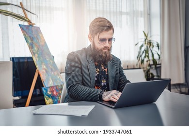 Portrait Of A Stylish Computer Programmer Wearing Custom Stylish Clothing With Sunglasses. Man Working On Laptop At Home.