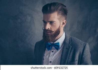 Portrait Of Stylish Hipster Brutal Young Man With Red Mustache, Beard And Beautiful Hairstyle Ready For Event Party While Standing On Gray Background.