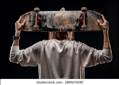 Portrait of a stylish man holding a skateboard in the Studio. Close-up of a smiling skateboarder posing on a black background. - Powered by Shutterstock