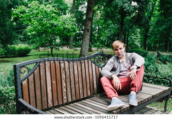 Portrait of a\
stylish man on a bench in the\
park.