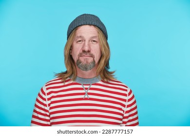 Portrait of stylish mature man with long hair looking at camera on blue background - Powered by Shutterstock