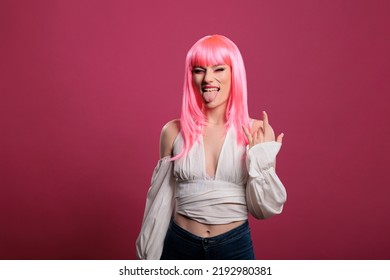 Portrait Of Stylish Punk Woman Doing Rock Sign And Sticking Tongue Out, Showing Aggressive Hipster Devil Gesture. Cool Female Rocker Advertising Funky Heavy Metal Symbol, Fooling Around.