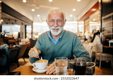 Portrait of stylish senior man stirring coffee with spoon in cafeteria and smiling at camera. - Powered by Shutterstock