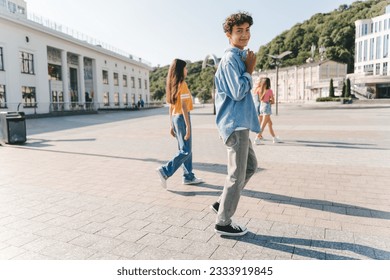 Portrait of stylish teenage boy wearing wireless headphone looking at camera walking on the street. Summer, positive lifestyle concept  - Powered by Shutterstock