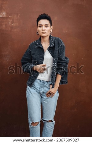 Portrait stylish woman a short hair in fashion  jean jacket on a red background. Trend women's haircut hairstyle. 