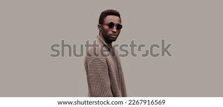 Portrait of stylish young african man model wearing knitted cardigan isolated on gray background