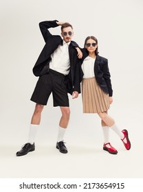 Portrait Of Stylish Young Couple, Man And Woman In Retro Suit Posing Isolated Over Grey Studio Background. Serious Look. Concept Of Retro Fashion, Art Photography, Style, Queer, Beauty