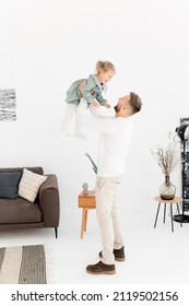 Portrait Of Stylish Young Father Lift In The Air Little Daughter, Playing With Her. Handsome Dad Holding In Arms His Lovely Baby Girl, Having Fun, Enjoying Joyful Moments, Concept Of Happy Family