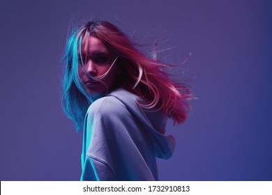 Portrait Of A Stylish Young Girl, Cool Posing In A Hoodie With Developing Hair, On A Neon Background.