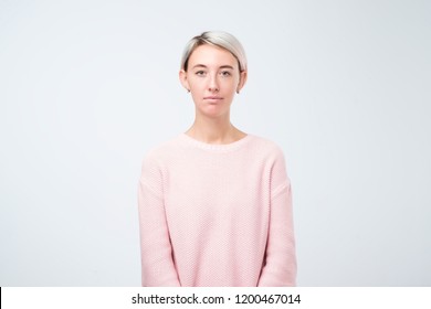 Portrait Of Stylish Young Pretty Woman Smiling Standing In Pink Sweater On White Studio Background. Simple Not Emotional Face