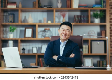 Portrait Of A Successful Asian Businessman In A Classic Office Working On A Laptop, Smiling