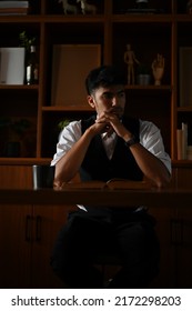 Portrait Of A Successful Asian Male CEO Or Businessman Pensive Focused Thinking His Strategy Plan In Modern Dark Private Office Room.