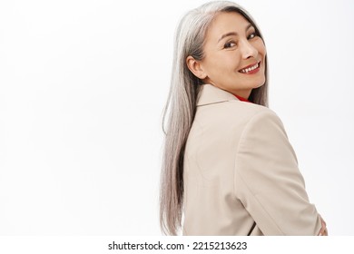 Portrait Of Successful Asian Senior Businesswoman, Smiling And Looking Happy, Professional Power Pose, Corporate Outfit, Standing Over White Background