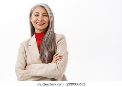 Portrait of successful asian senior businesswoman, smiling and looking happy, professional power pose, corporate outfit, standing over white background - Powered by Shutterstock