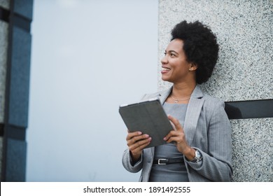 Portrait of a successful black business woman using digital tablet during quick break in front a corporate building. - Powered by Shutterstock