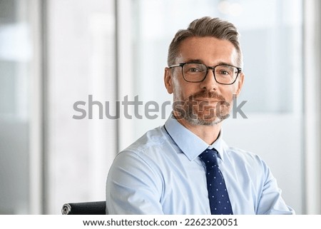Portrait of successful business man with eyewear in office. Happy and smiling businessman standing in office while looking at camera with copy space. Portrait of handsome mature man in a workplace.