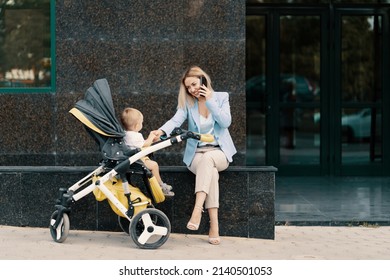 Portrait Of A Successful Business Woman In Blue Suit With Baby. Business Woman Talking On The Phone