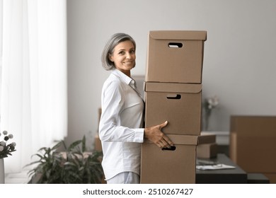 Portrait of successful business woman carrying large cardboard boxes stacked on top of each other, working in warehouse, surrounded by prepared parcels for shipment to clients. Order fulfilment, SME - Powered by Shutterstock