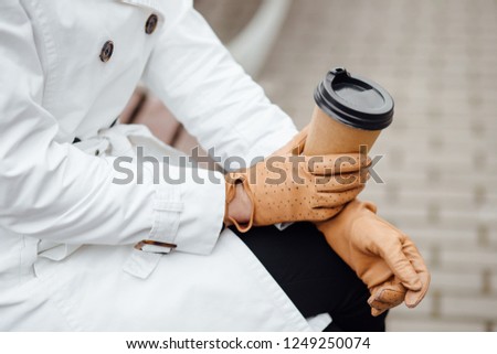 Portrait of successful business woman holding cup of hot drink in hand on her way to work on city street. Beautiful woman with coffee cup near office building.