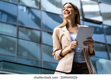 Portrait successful business woman using digital tablet in front modern business building