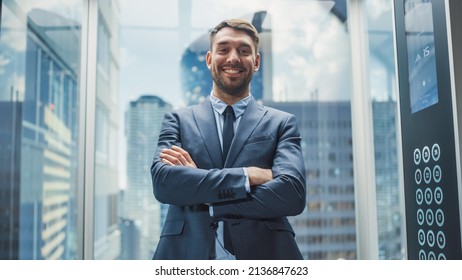 Portrait of a Successful Businessman in a Suit Riding Glass Elevator to Office in Modern Business Center. Male Looking at the Camera, Crossing Arms, Charmingly Smiling and Striking a Pose. - Powered by Shutterstock