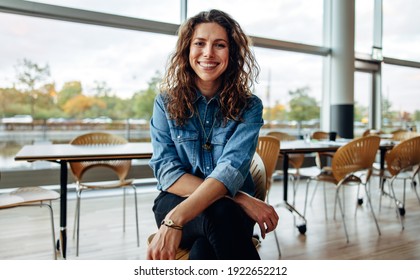 Portrait of a successful businesswoman sitting in office. Beautiful female professional looking at camera and smiling.