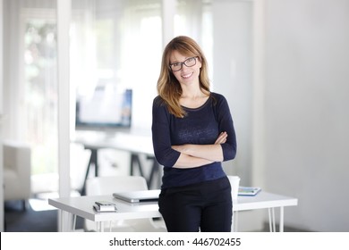 Portrait Of Successful Businesswoman Standing With Arms Crossed At The Office. Mature Professional Woman Looking At Camera And Smiling.