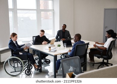 Portrait of successful businesswoman using wheelchair while leading business meeting in office with diverse group of people, copy space