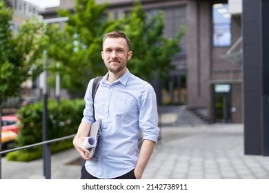 Portrait Of Successful And Confident Real Estate Agent, Businessman Or Financial Manager. Smiling Successful Stylish Bearded Business Man Standing On A Street With Urban Background. High Quality Image