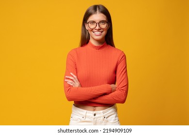 Portrait Of Successful Confident Woman Entrepreneur In Glasses And Red Business Casual Outfit Standing On Yellow Background With Crossed Arms And Decisive Happy Facial Expression