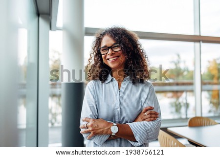 Portrait of successful female professional with her arms crossed. Smiling businesswoman standing in office.