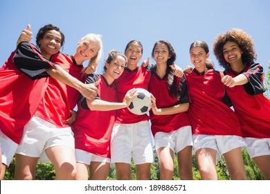 Portrait of successful female soccer players gesturing thumbs up against clear blue sky - Powered by Shutterstock