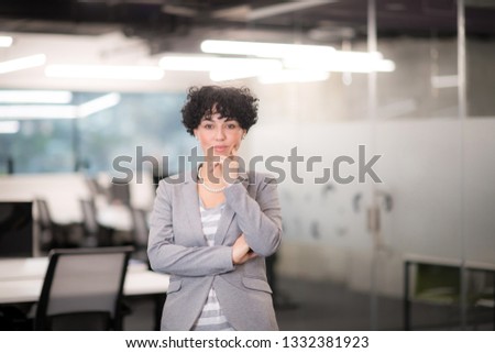 Portrait of successful female software developer with a curly hairstyle at modern startup office