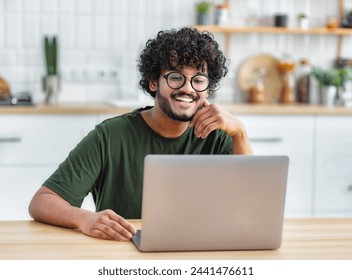 Portrait of successful freelancer or student working on new project. Smiling young indian man using laptop to work remotely from home - Powered by Shutterstock