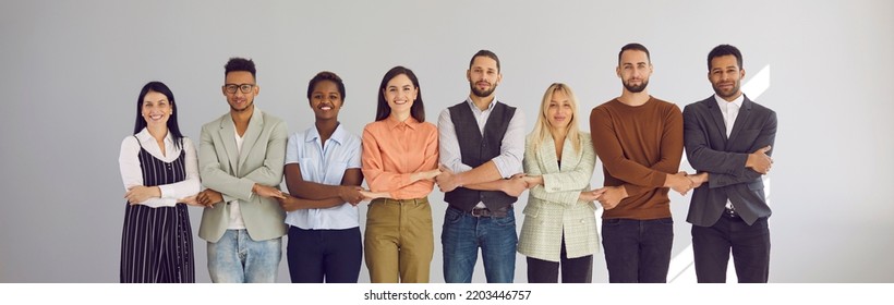 Portrait Of Successful Group Of Business People Standing Together In Row And Holding Hands. Multiracial People On Light Background. Concept Of Strong Community, Mutual Assistance And Support. Banner.