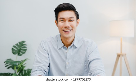 Portrait of successful handsome executive businessman smart casual wear looking at camera and smiling, happy in modern office workplace. Young Asia guy talk to colleague in video call meeting at home. - Shutterstock ID 1979702273