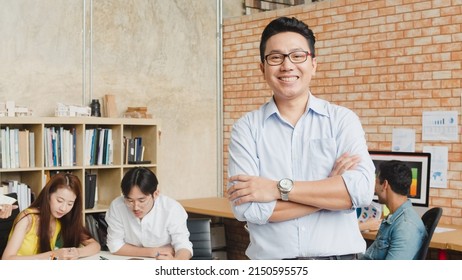 Portrait Of Successful Handsome Executive Businessman Smart Casual Wear Looking At Camera And Smiling, Arms Crossed In Modern Office Workplace. Young Asia Guy Standing In Contemporary Meeting Room.