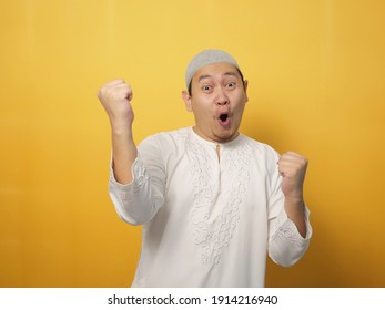 Portrait Of Successful Happy Muslim Man Screaming Shouting And Shows Winning Victory Gesture Over Yellow Background