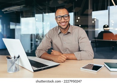 Portrait of successful investor, african american man smiling and looking at camera, man working inside office using laptop at work, satisfied with achievement result. - Powered by Shutterstock