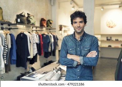Portrait of successful male owner  with crossed arms in clothing store. Looking at camera