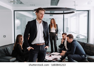 Portrait of successful manager looking at camera on the background of talking people