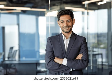 Portrait of successful mature boss, senior businessman in business suit looking at camera and smiling, man with crossed arms working inside modern office building
